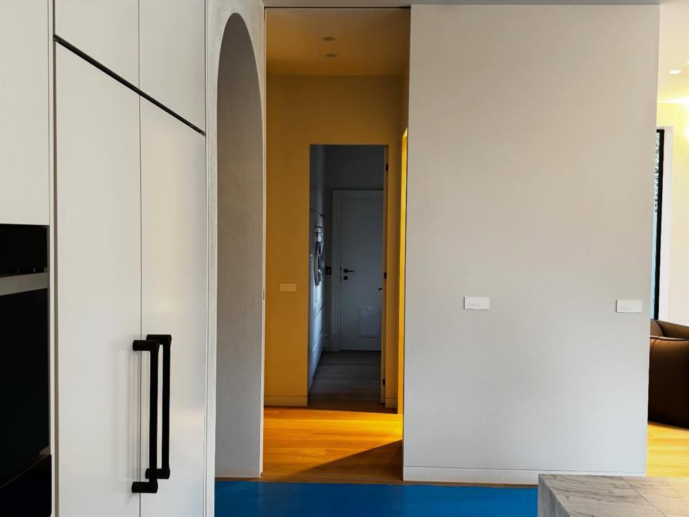 Hallway with dark joinery and an arched opening onto a warmly lit corridor.