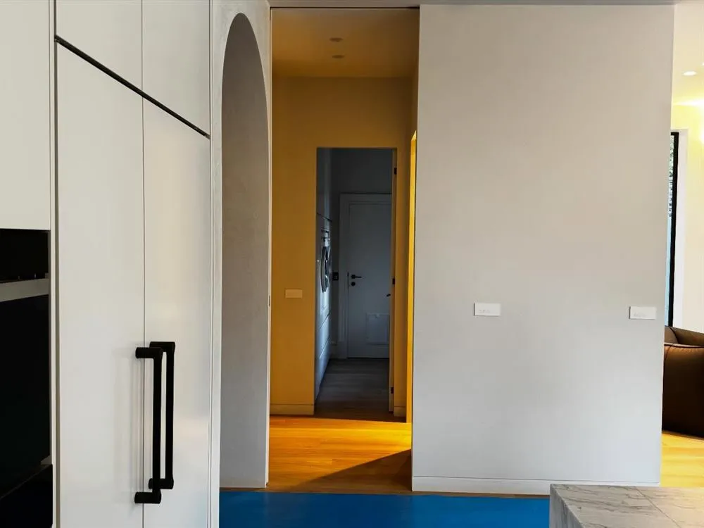 Hallway with dark joinery and an arched opening onto a warmly lit corridor.