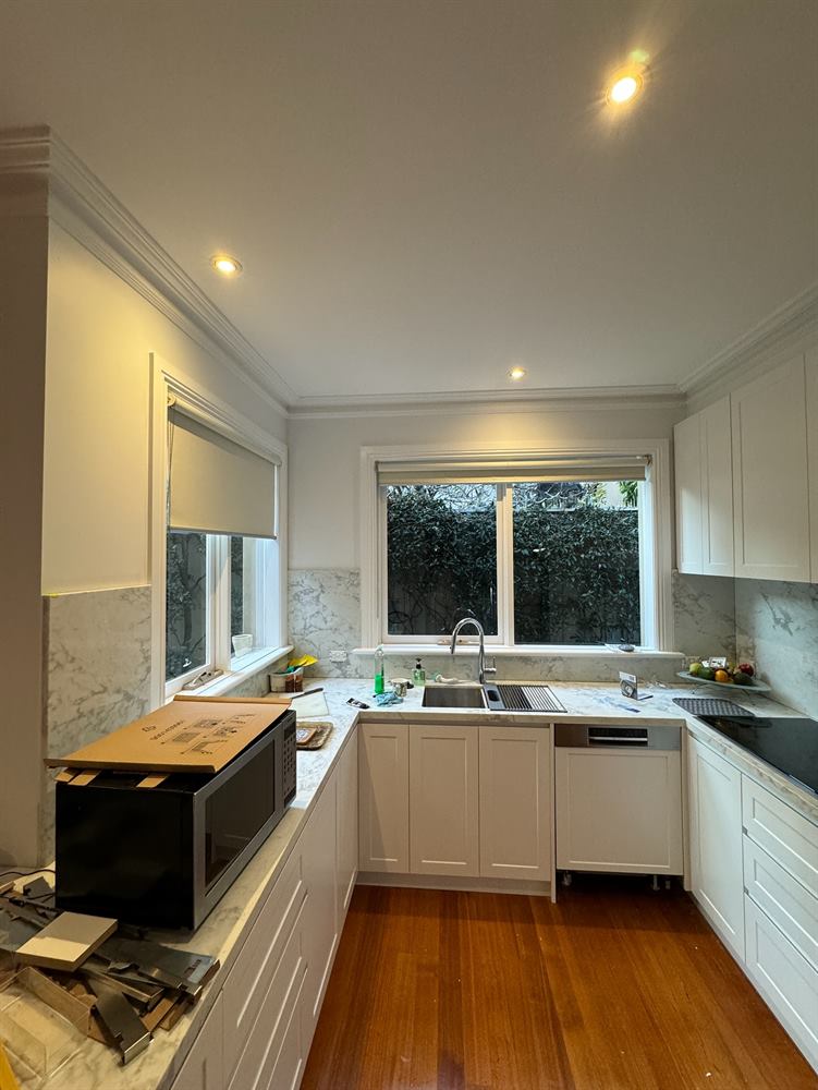 Kitchen with white cabinetry and a window over the sink, photographed mid-installation.
