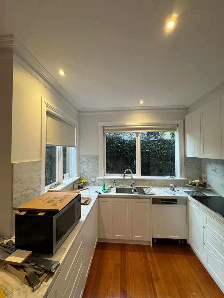 Kitchen with white cabinetry and a window over the sink, photographed mid-installation.