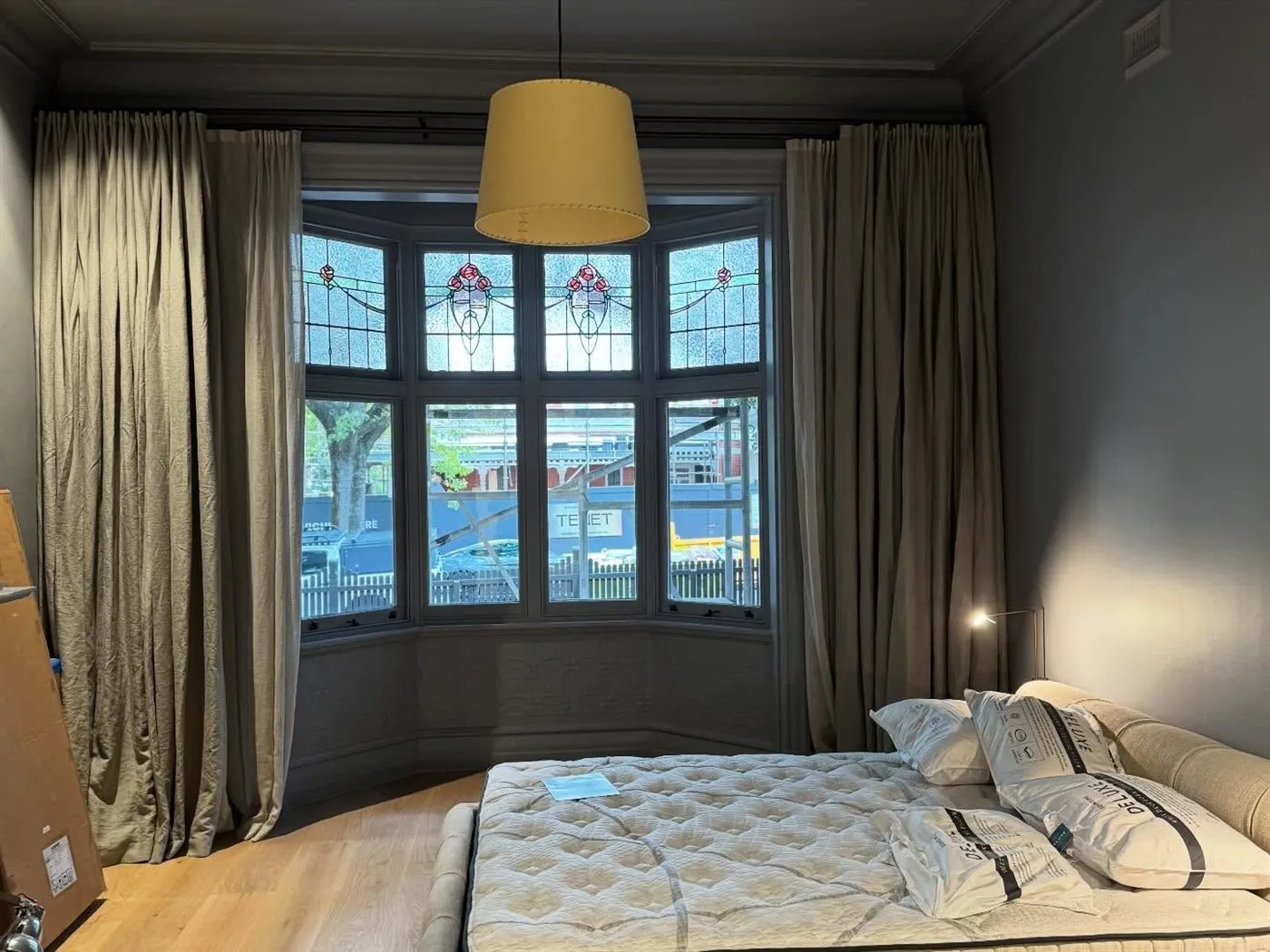 Bedroom with a leadlight bay window, heavy curtains and a drum pendant light.