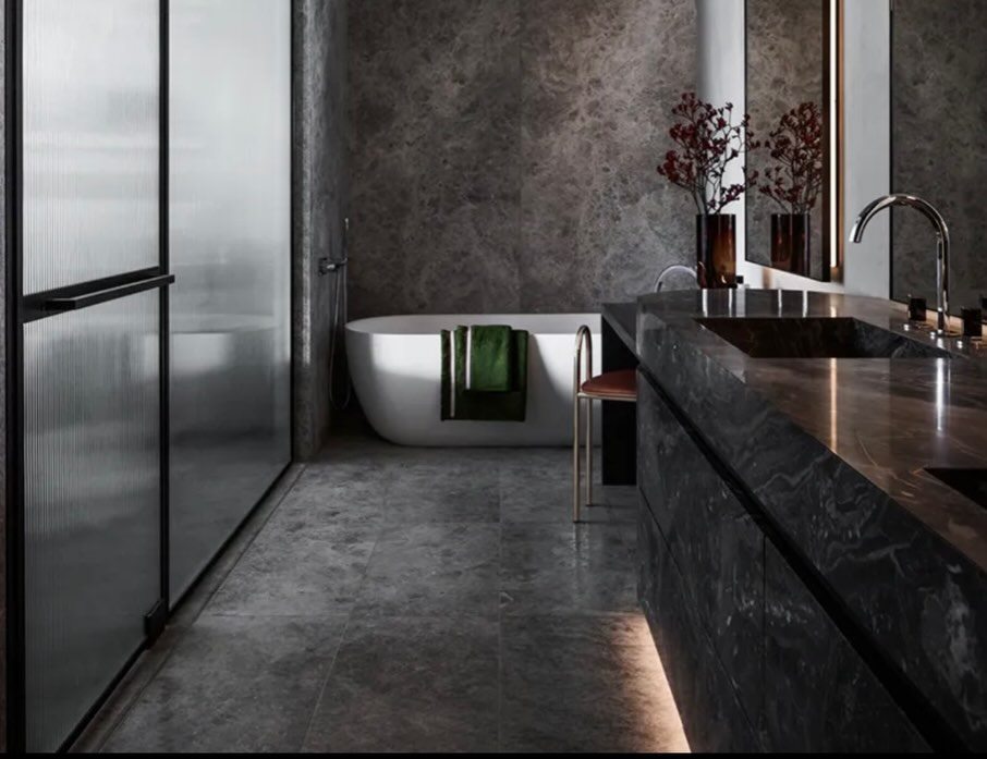 Bathroom in dark veined stone with a freestanding bath, walk-in shower and stone vanity.